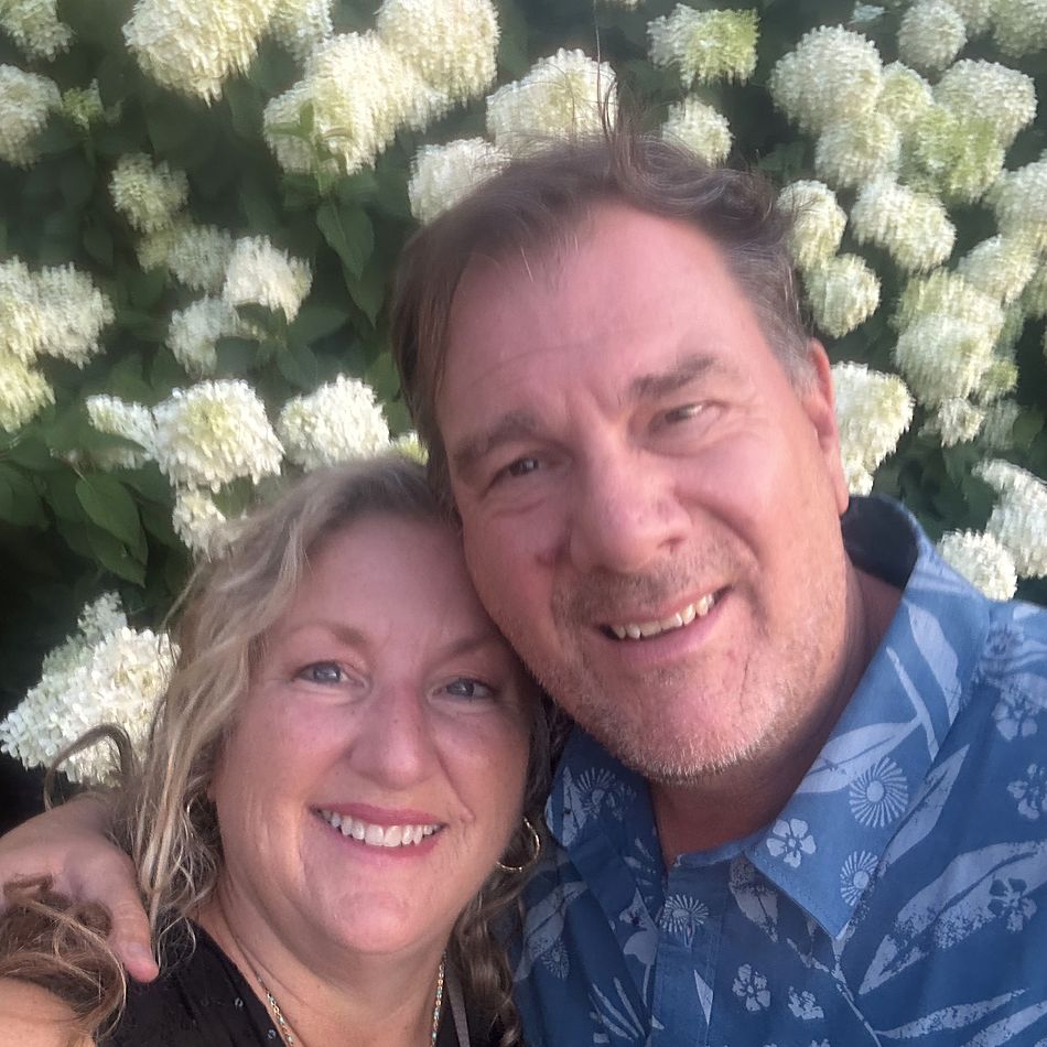John and Jacque together in front of a hydrangea bush in the evening light.
